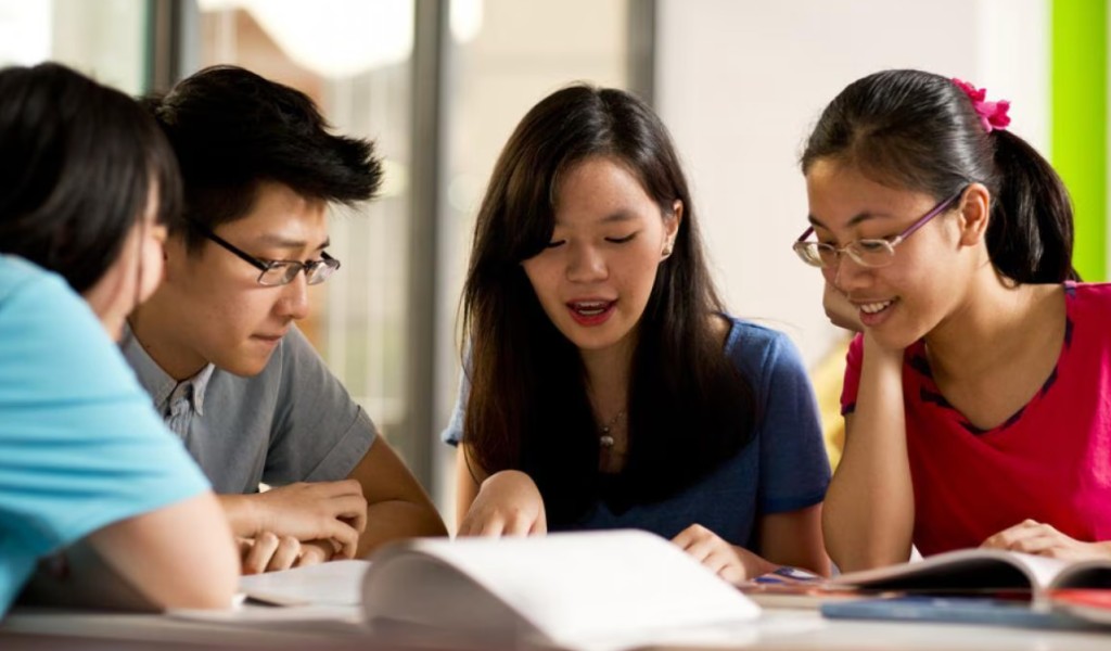 Students collaborating and studying together around a table with books